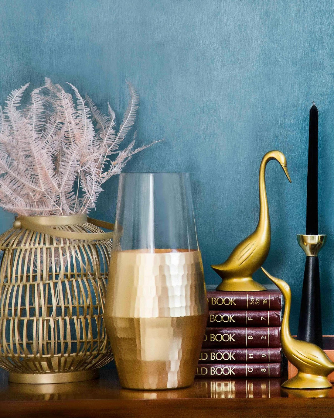 A selection of vintage homeware items including a vase, 2 brass ducks, a candleholder and a stack of books