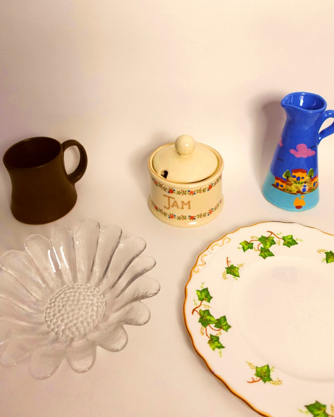 A selection of vintage homeware on a white background, including a plate, a jam pot and a small ceramic vase