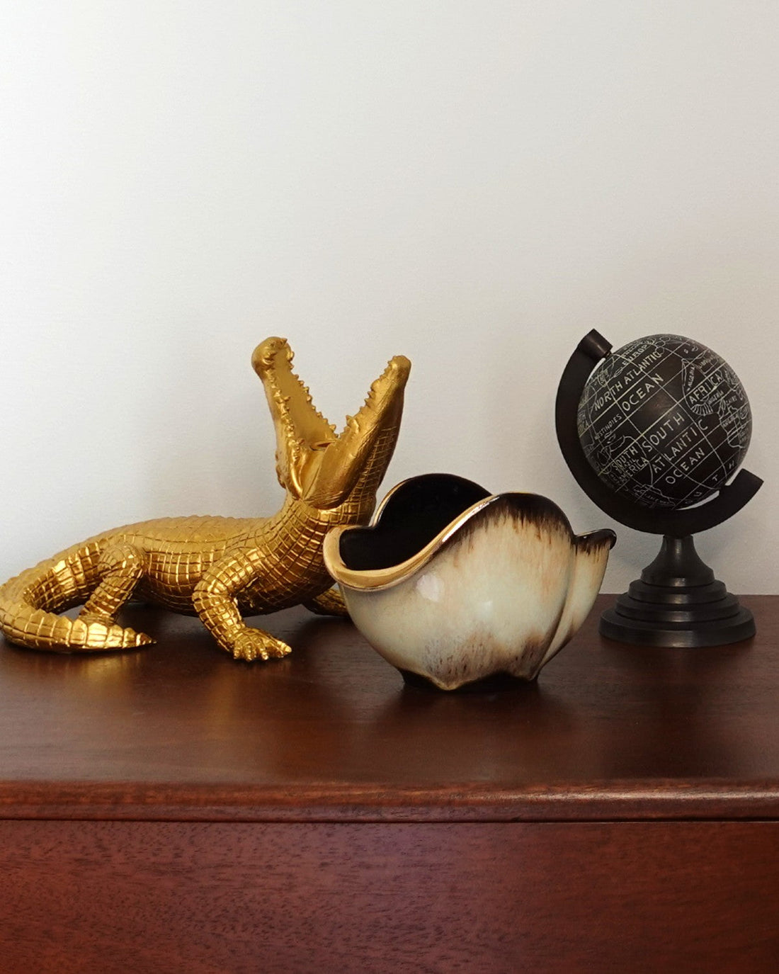 A selection of vintage homeware sitting on a dark wood chest of drawers