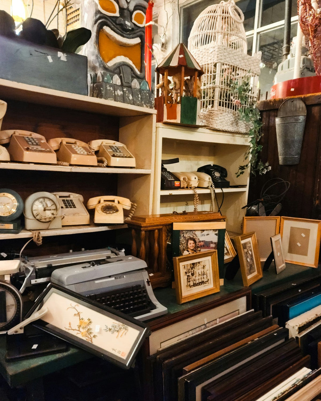 A selection of vintage items in a shop including a typewriter and a selection of old telephones